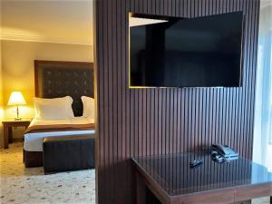 a hotel room with a bed and a television on a wall at Maxi Park Hotel & Spa in Velingrad