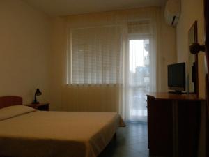 Schlafzimmer mit einem Bett, einem TV und einem Fenster in der Unterkunft Family Hotel Maritime in Achtopol