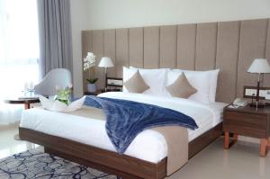 a bed with a white comforter and pillows in a room at JUFFAIR BOULEVARD HOTEL & SUITES in Juffair