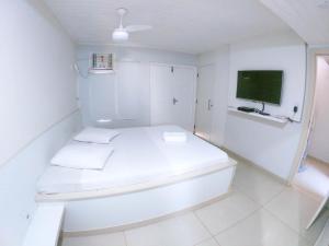Habitación blanca con cama y TV de pantalla plana. en Ilha Flat Boganville, en Abraão