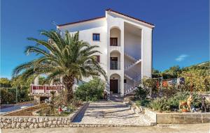 a white house with a palm tree in front of it at Awesome Apartment In Banjol With 2 Bedrooms And Wifi in Banjol