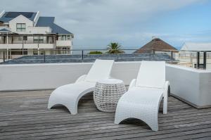 two white chairs and a table on a roof at Le Paradis Penthouse in Hermanus