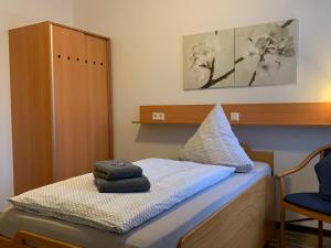 ein kleines Zimmer mit einem Bett mit einem blauen Stuhl in der Unterkunft Landgasthaus-Hotel Wenninghoff in Dreierwalde