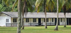uma casa amarela e branca com palmeiras em frente em The Saddle Resort em Kuantan