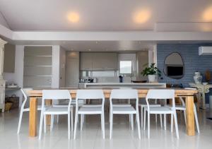 a kitchen with a wooden table and white chairs at Le Paradis Penthouse in Hermanus