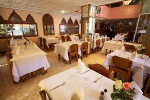 a restaurant with white tables and chairs with flowers on them at Hotel Tachfine in Marrakesh