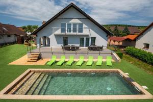 dom z basenem z zielonymi leżakami w obiekcie Aranyeső Apartmanházak No.1 w mieście Balatonalmádi