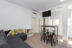 a living room with a couch and a table with stools at Alma Suites Madrid CH in Madrid