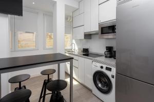 a kitchen with a washing machine and two bar stools at Alma Suites Madrid CH in Madrid