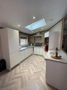 a kitchen with white cabinets and a wooden floor at Lotus Lodge with Hot Tub in York