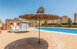 a large straw umbrella in front of a pool at Pet Friendly Apartment in Oropesa del Mar