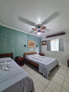 a bedroom with two beds and a ceiling fan at Pousada Porto do Itagua in Ubatuba