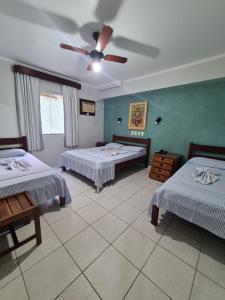 a bedroom with two beds and a ceiling fan at Pousada Porto do Itagua in Ubatuba