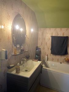 W łazience znajduje się umywalka, lustro i wanna. w obiekcie Chambres chez Nanou avec petit déjeuner w mieście Chimay