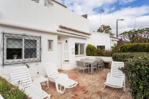 a patio with white chairs and a table at Townhouse Seraphina in Vale do Lobo