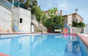 a swimming pool with chairs and a house at Cozy Apartment In Talasani in Talasani