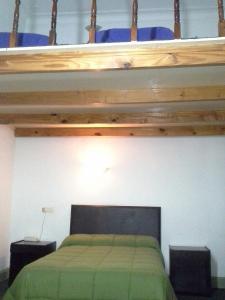a bedroom with a loft bed with a green bedspread at Hotel del Prado in Buenos Aires
