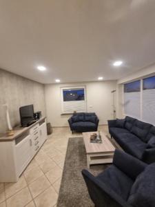 a living room with blue couches and a tv at Apartmenthaus Robbe Luv in Neuharlingersiel