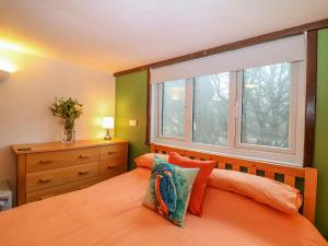 1 dormitorio con cama de color naranja y ventana en Kingfisher Cottage, en Holsworthy
