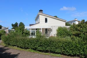 une maison blanche avec des buissons devant elle dans l'établissement Casa Ostrea, à Kamperland