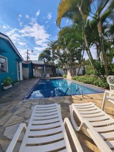 a swimming pool with two lounge chairs next to a house at Pousada Porto do Itagua in Ubatuba