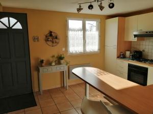 eine Küche mit einem Tisch, einem Fenster und einer Tür in der Unterkunft Gîte berneval le grand in Berneval-le-Grand