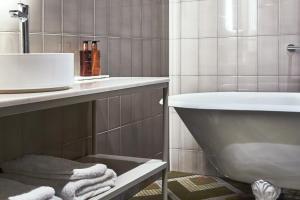 a bathroom with a tub and a sink and towels at Solo Sokos Hotel Torni Helsinki in Helsinki