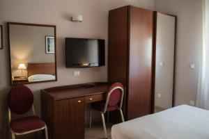 a hotel room with a desk and a tv on the wall at Hotel Mediterraneo in Palermo