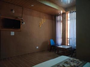 a room with a tv and a chair and a table at Hotel Cozy Haven in Mandi
