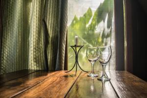 two wine glasses sitting on a wooden table with a candle at Casa Gaia Cabo Polonio in Cabo Polonio