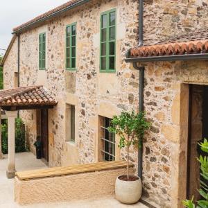 a stone house with a potted tree in front of it at CASA CON ENCANTO (o Refuxio) in Merza