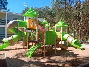 a playground with a green slide in the sand at Jantar in Łazy