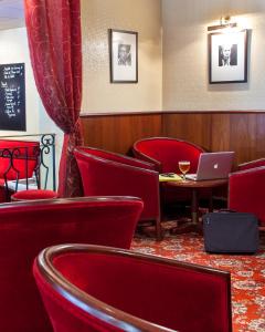 un restaurant avec des chaises rouges et un ordinateur portable sur une table dans l'établissement BRIT HOTEL Le Lion d'Or CHINON, à Chinon