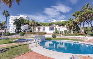 uma piscina com palmeiras e um edifício em Nice Apartment In Calahonda With Outdoor Swimming Pool em Sitio de Calahonda