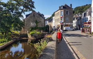 a woman walking down a street next to a river at Nice Home In Riec Sur Belon With 3 Bedrooms in Riec-sur-Bélon