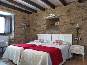 2 camas en un dormitorio con pared de piedra en Casa do Horreo, en O Pino 
