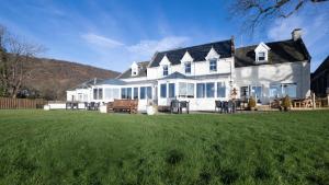 ein großes weißes Haus mit einem großen Hof in der Unterkunft Karma Lake Of Menteith Hotel in Aberfoyle