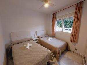 two beds in a small room with a window at Apartamentos Las Rosas de Capistrano in Nerja