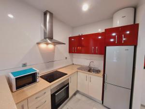 cocina con armarios rojos y nevera blanca en Apartamentos Las Rosas de Capistrano, en Nerja