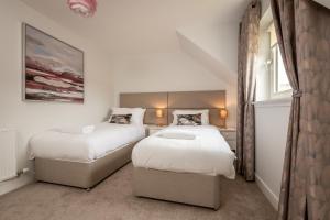 2 Betten in einem kleinen Zimmer mit weißen Wänden in der Unterkunft Kingsbarns Village Green - Walk to Beach - Parking in Kingsbarns