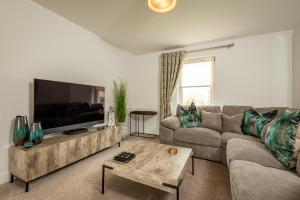 a living room with a couch and a flat screen tv at Kingsbarns Village Green - Walk to Beach - Parking in Kingsbarns