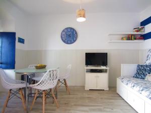 uma sala de estar com uma mesa, um sofá e um relógio em A Praia da Messejana em Messejana