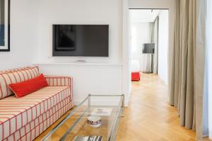 Hotel Morfeo في ميلانو: غرفة معيشة مع أريكة وتلفزيون على الحائط