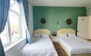 2 łóżka w sypialni z zieloną ścianą w obiekcie Khách Sạn Lý Sơn Phú Sỹ w mieście Ly Son