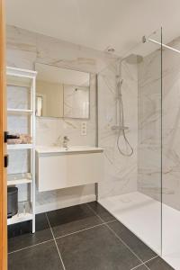 een badkamer met een wastafel en een douche bij Maison Emile in De Panne