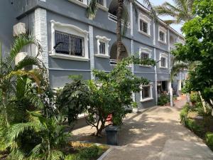 a blue building with trees in front of it at Calabash Apartment-Hotel in Kotu