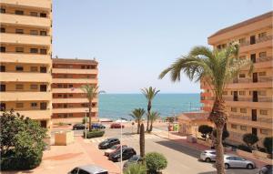 uma rua com palmeiras e um edifício e o oceano em Beautiful Apartment In Torrevieja With Kitchenette em La Mata