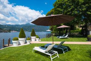 een paar stoelen en een paraplu op het gras bij Bifora65 flats and garden - Lakeview in Orta San Giulio
