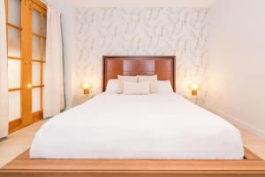 1 dormitorio con 1 cama blanca grande y 2 lámparas en BHost - The Special One, en Málaga
