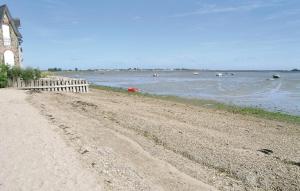 a beach with a fence and boats in the water at Amazing Home In Quettehou in Quettehou +3 photos
